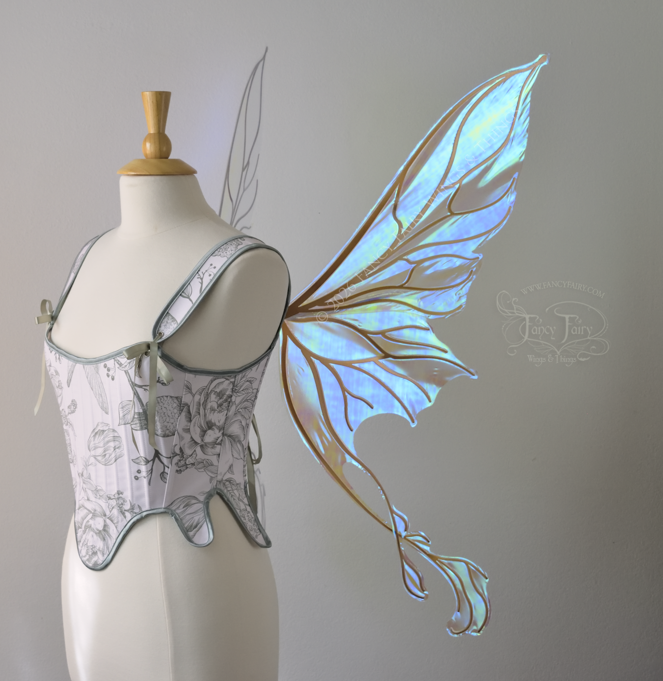 Transparent blue / green iridescent fairy wings with pointed upper tips and 2 swirling tails on the bottom panels with copper veins, worn on a dress form, right side view