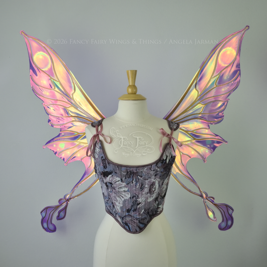 Large iridescent fairy wings with long double tails, in shades of plum, rose, and touches of green with copper veins, worn on a dress form. Front View.

