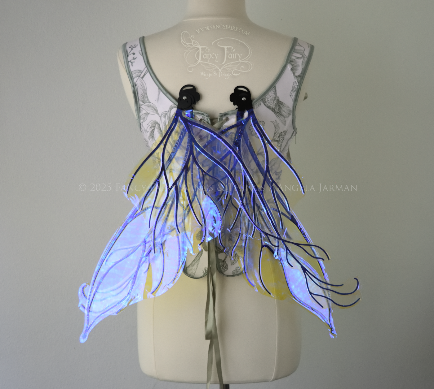 Violet iridescent fairy wings with pointed upper tips and 2 swirling tails on the bottom panels with black veins, worn on a dress form, back view, in resting position
