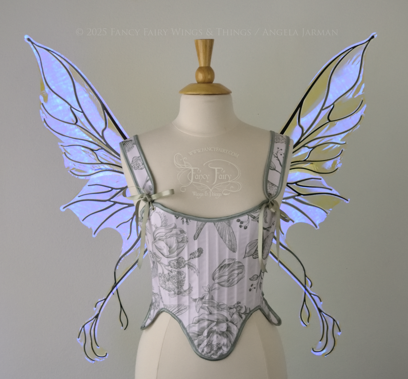 Violet iridescent fairy wings with pointed upper tips and 2 swirling tails on the bottom panels with black veins, worn on a dress form, front view