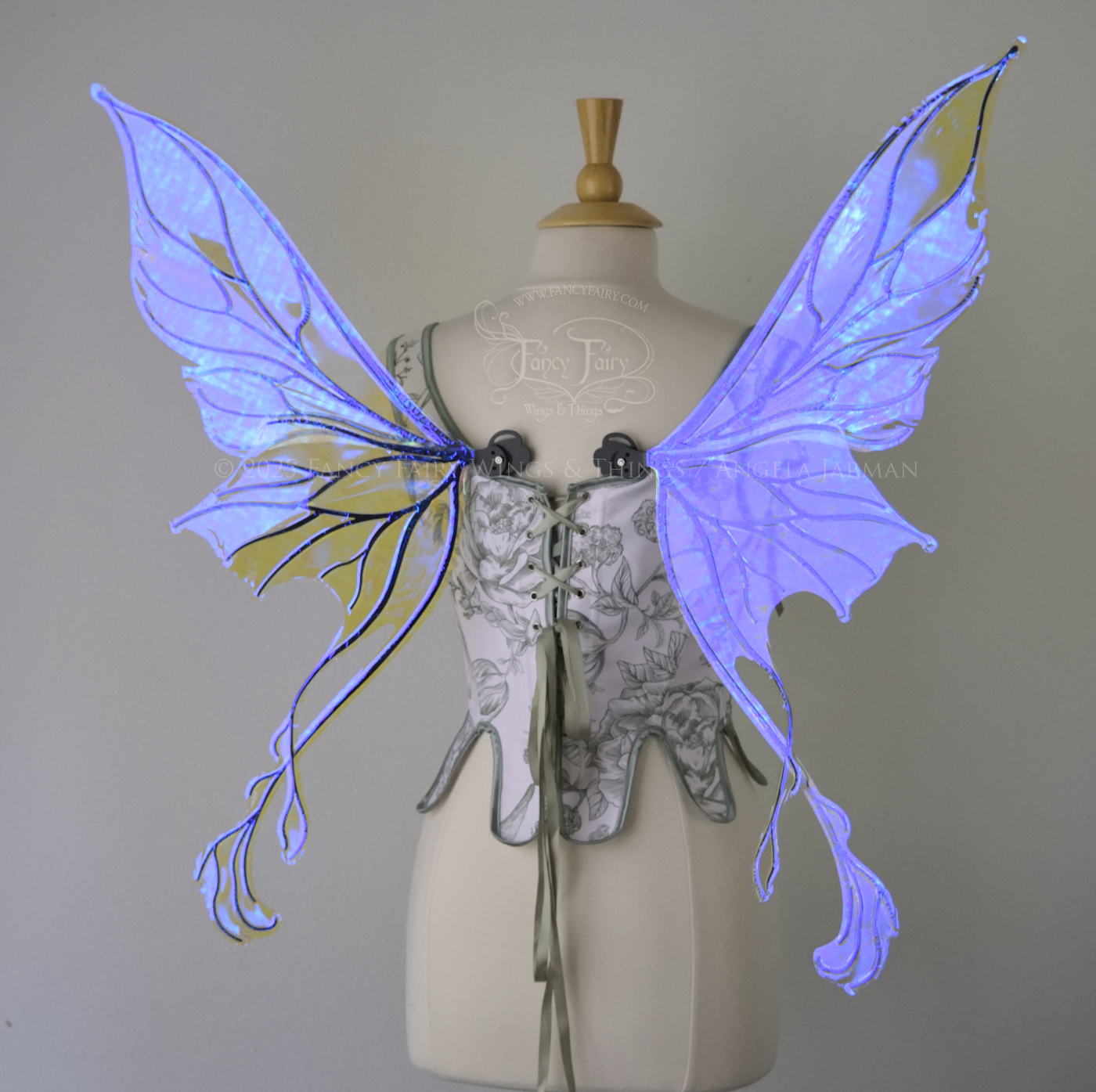 Violet iridescent fairy wings with pointed upper tips and 2 swirling tails on the bottom panels with black veins, worn on a dress form, back view