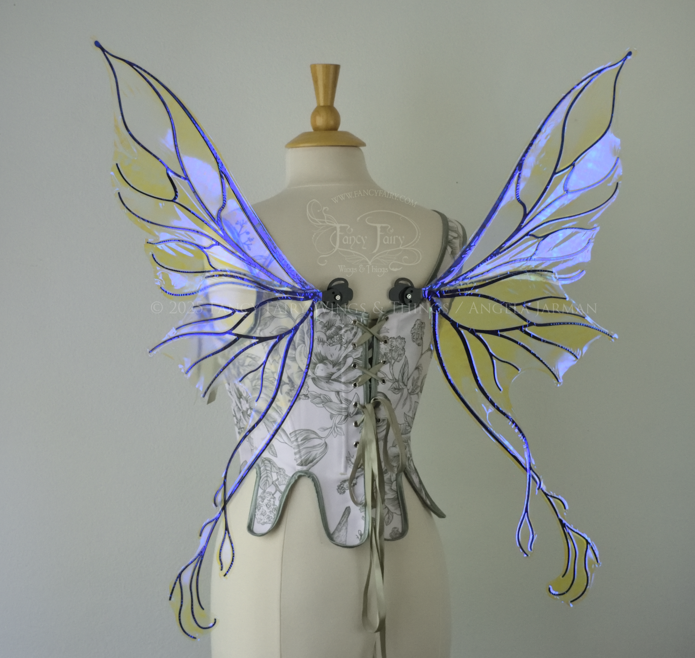 Violet iridescent fairy wings with pointed upper tips and 2 swirling tails on the bottom panels with black veins, worn on a dress form, back view