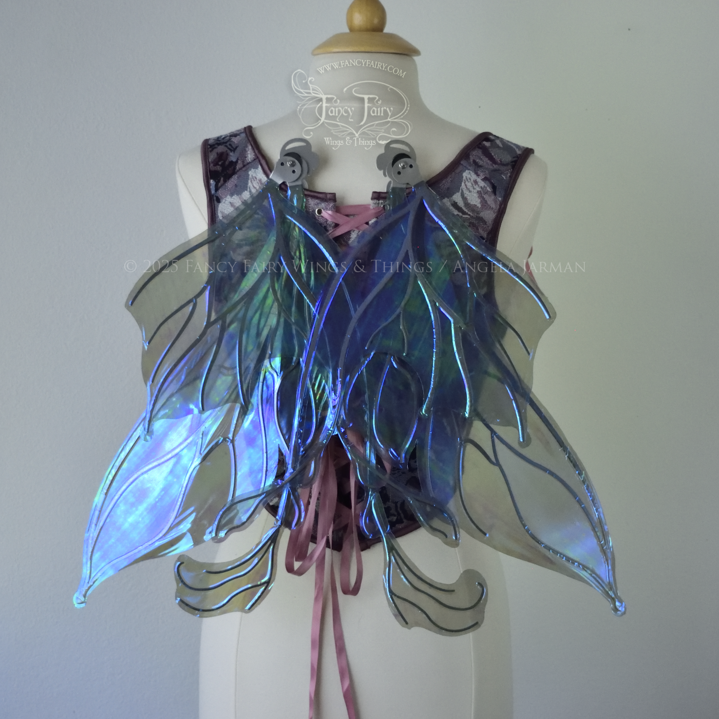 Transparent blue / purple / grey iridescent fairy wings with pointed upper tips and 2 swirling tails on the bottom panels with silver veins, worn on a dress form, back view, in resting position