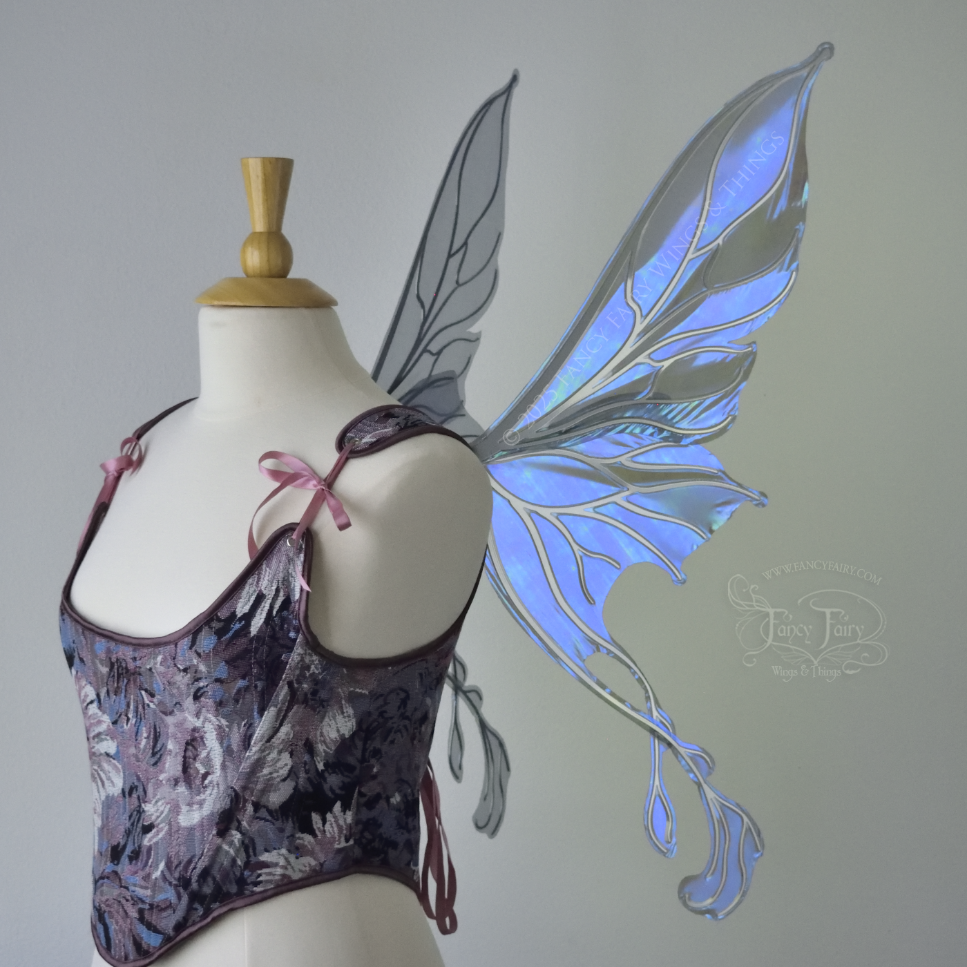 Transparent blue / purple / grey iridescent fairy wings with pointed upper tips and 2 swirling tails on the bottom panels with silver veins, worn on a dress form, right side view