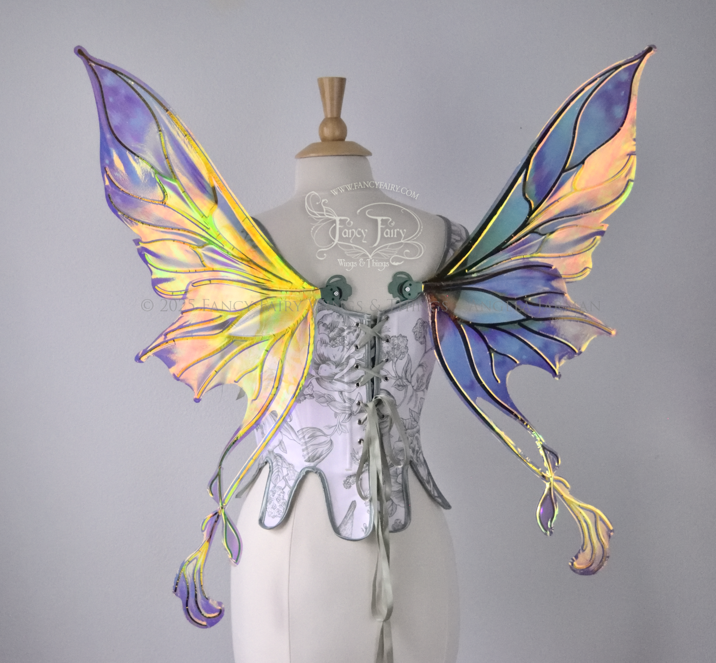 Painted iridescent fairy wings with pointed upper tips and 2 swirling tails on the bottom panels with green veins, worn on a dress form, back view