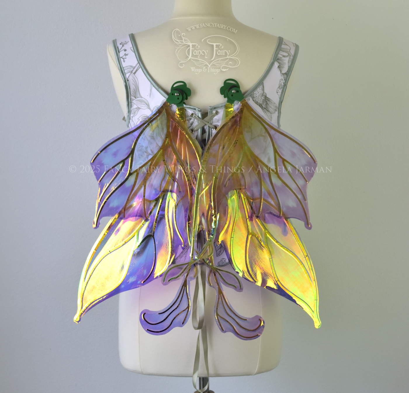 Painted iridescent fairy wings with pointed upper tips and 2 swirling tails on the bottom panels with green veins, worn on a dress form, back view, in resting position