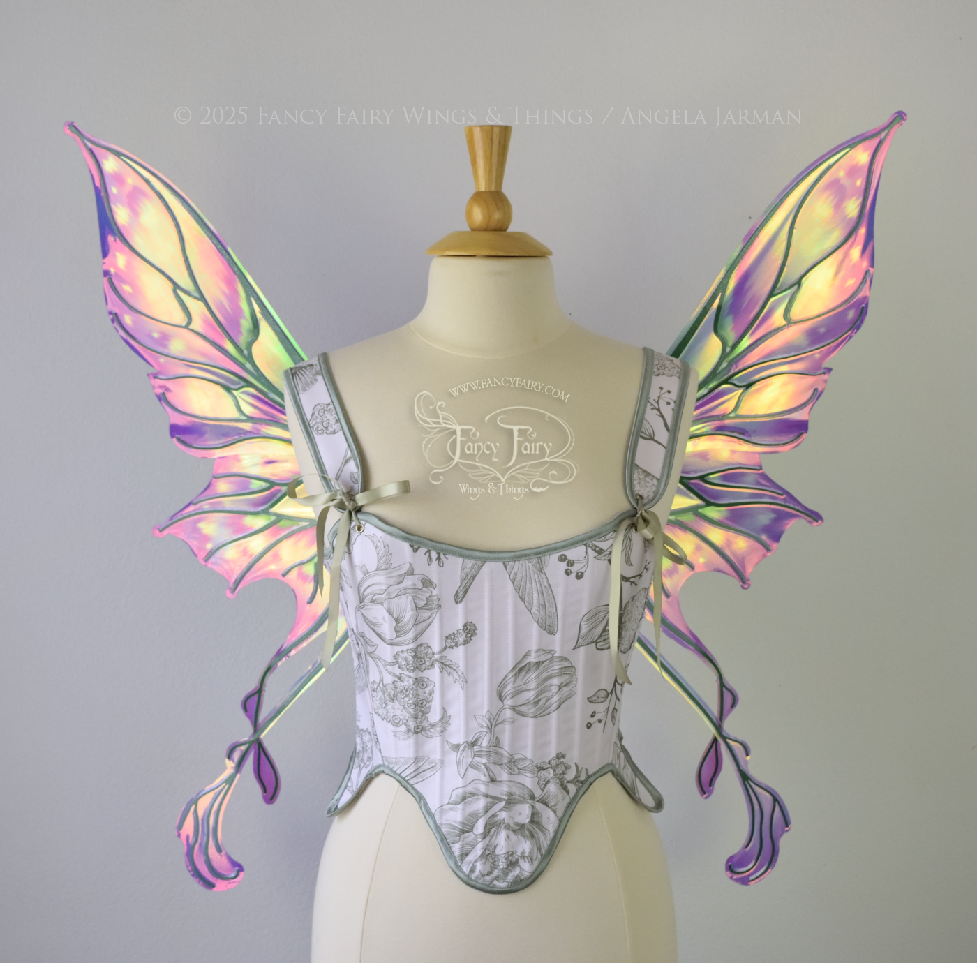 Painted iridescent fairy wings with pointed upper tips and 2 swirling tails on the bottom panels with green veins, worn on a dress form, front view