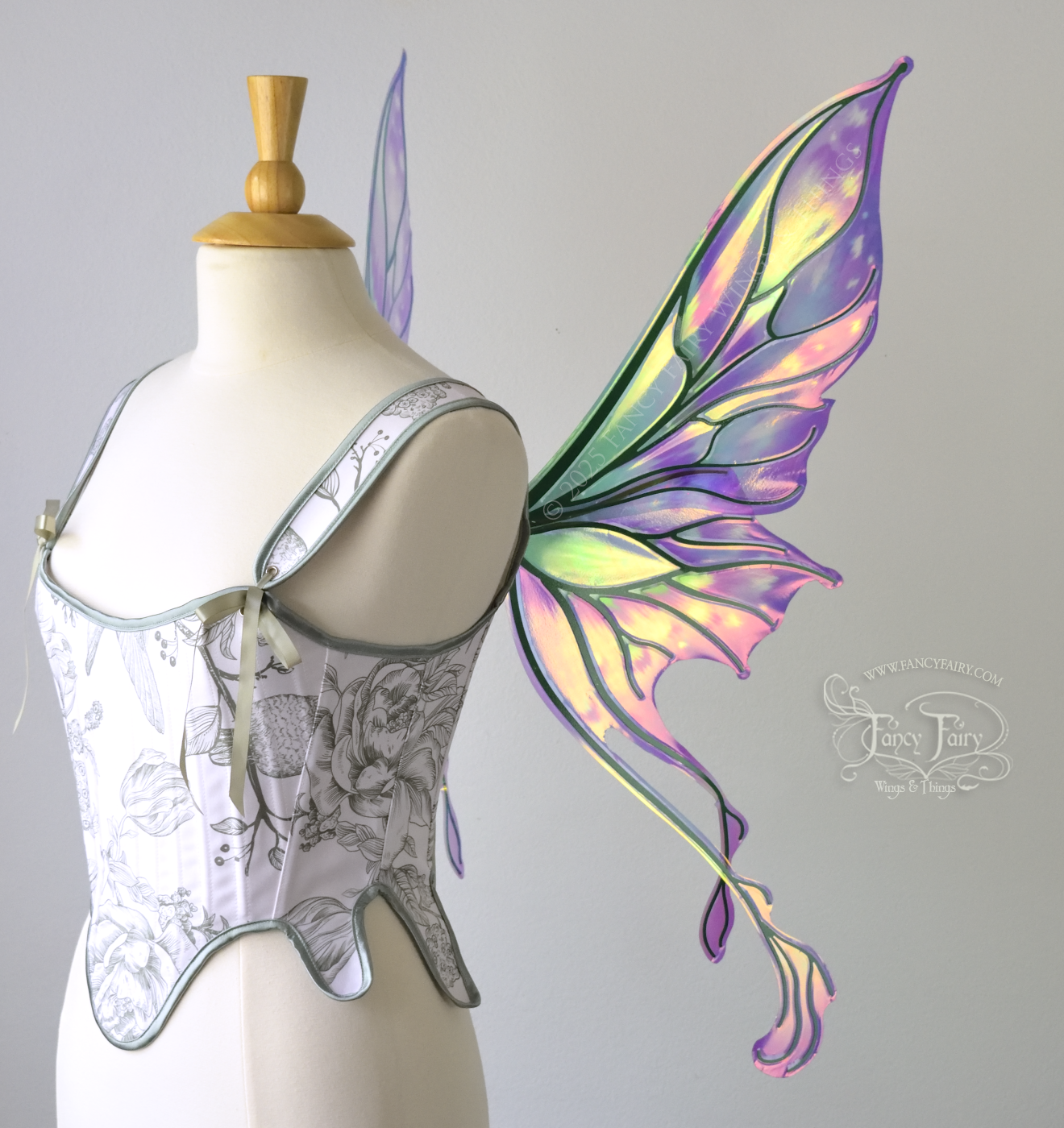Painted iridescent fairy wings with pointed upper tips and 2 swirling tails on the bottom panels with green veins, worn on a dress form, right side view