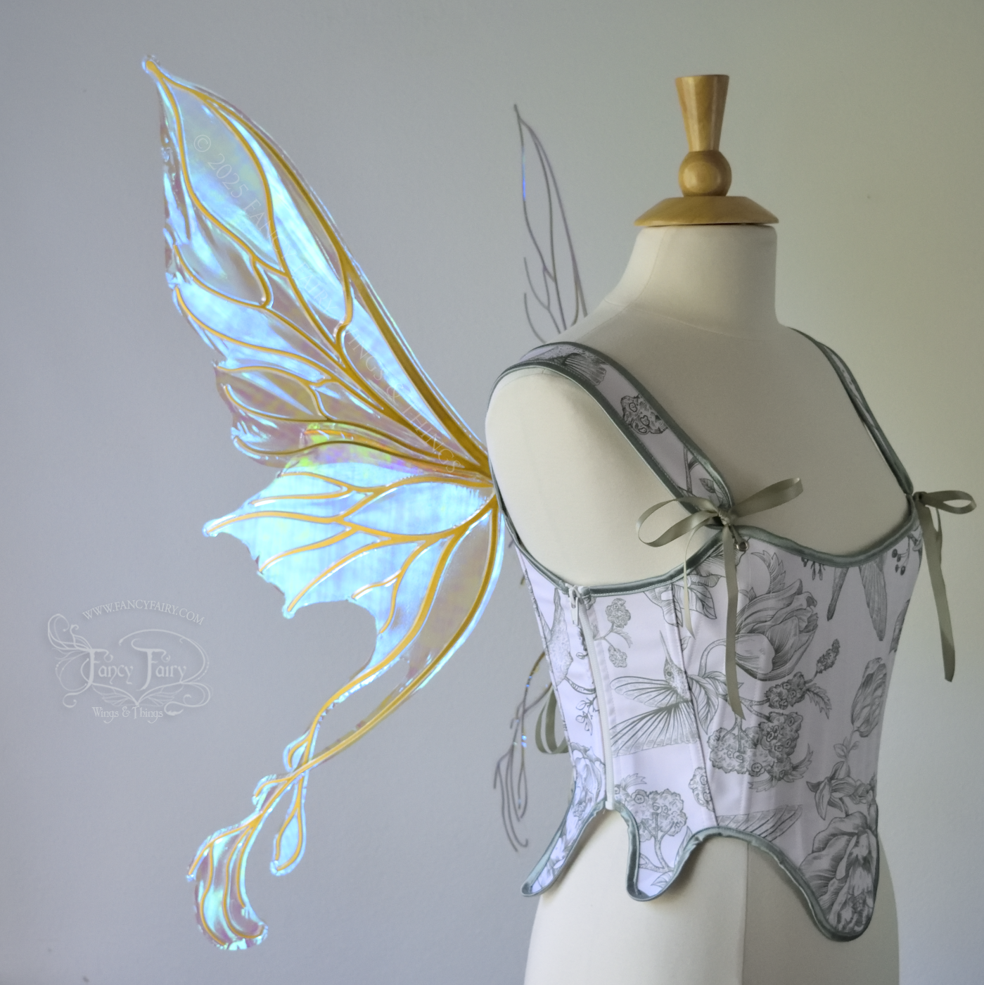 Transparent blue / green iridescent fairy wings with pointed upper tips and 2 swirling tails on the bottom panels with gold veins, worn on a dress form, left side view