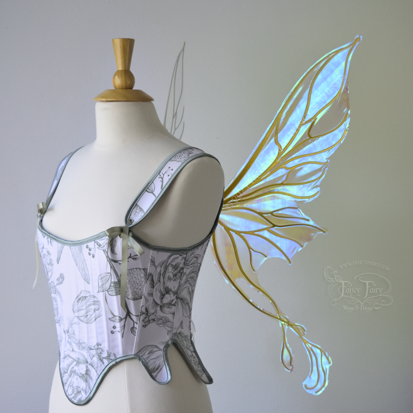 Transparent blue / green iridescent fairy wings with pointed upper tips and 2 swirling tails on the bottom panels with gold veins, worn on a dress form, right side view