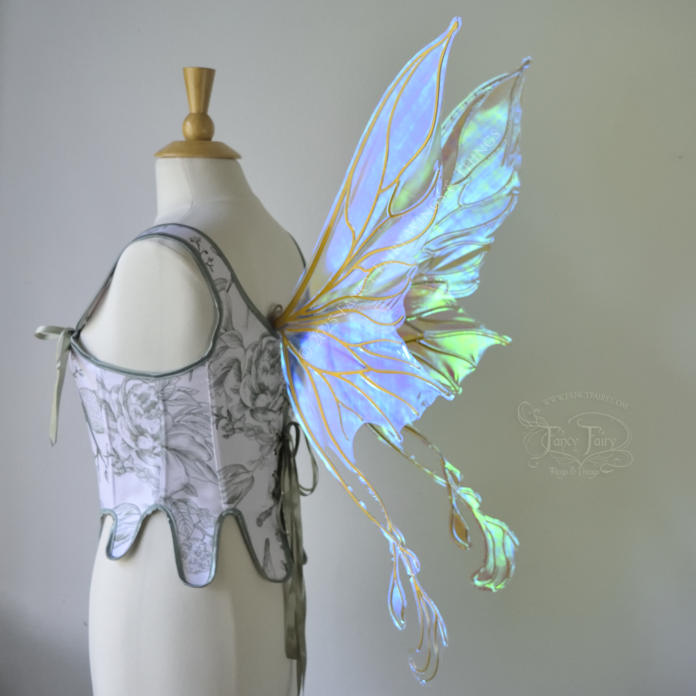 Transparent blue / green iridescent fairy wings with pointed upper tips and 2 swirling tails on the bottom panels with gold veins, worn on a dress form, back 3/4 side view