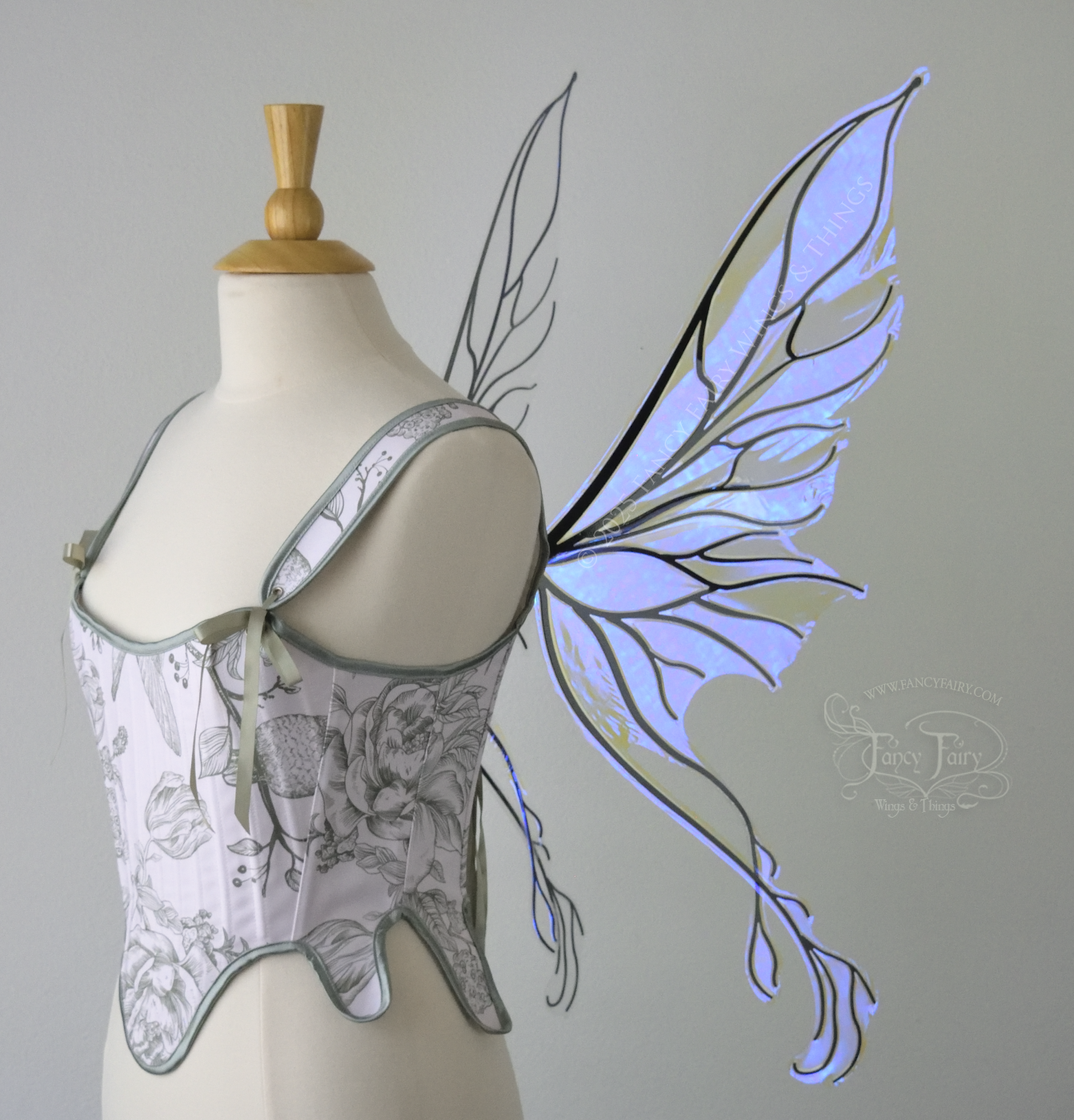 Violet iridescent fairy wings with pointed upper tips and 2 swirling tails on the bottom panels with black veins, worn on a dress form, right side view