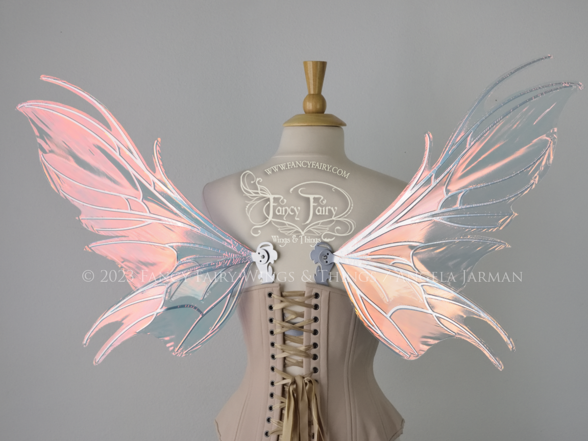Back view of a dress form wearing an underbust corset & pink iridescent fairy wings with a spikey shape, with silver veins