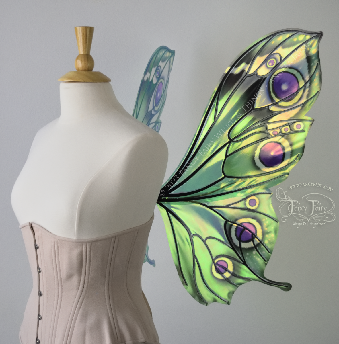 Right side view of iridescent green, black and fuchsia costume fairy wings, worn on a dressform