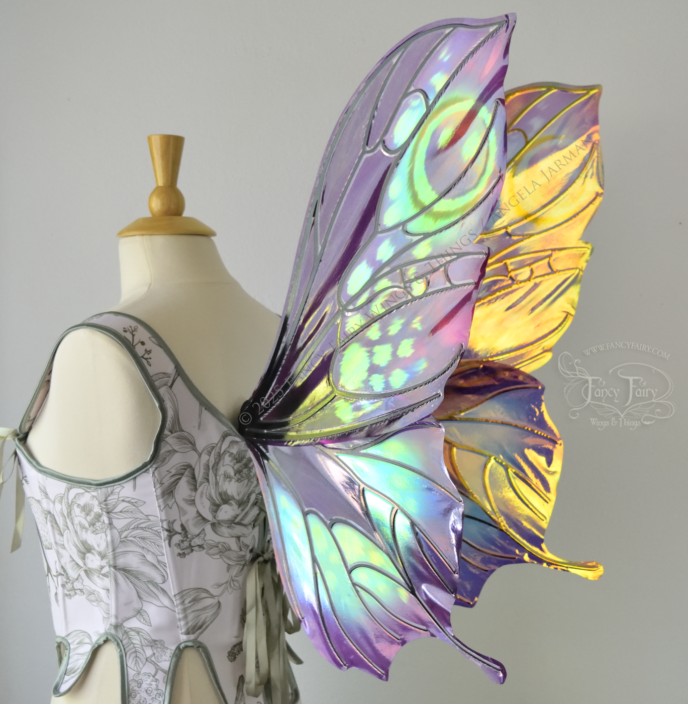 Iridescent fairy wings with a butterfly-like shape and short 'tails' in purples & blues with touches of pink & orange, back 3/4 view