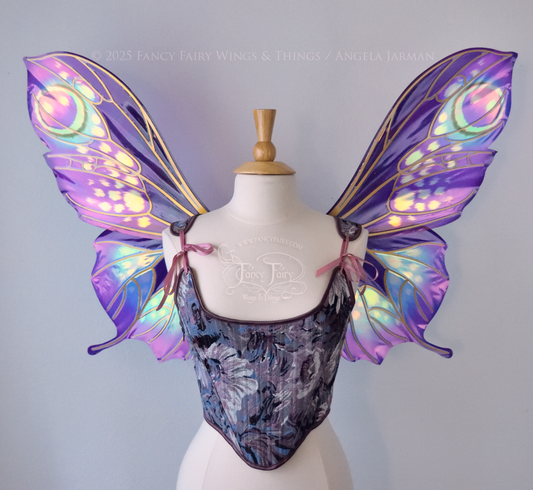 Large butterfly-esque iridescent fairy wings in shades of plum purple, blue and pink with art nouveau style gold veins, worn on a dress form, front view