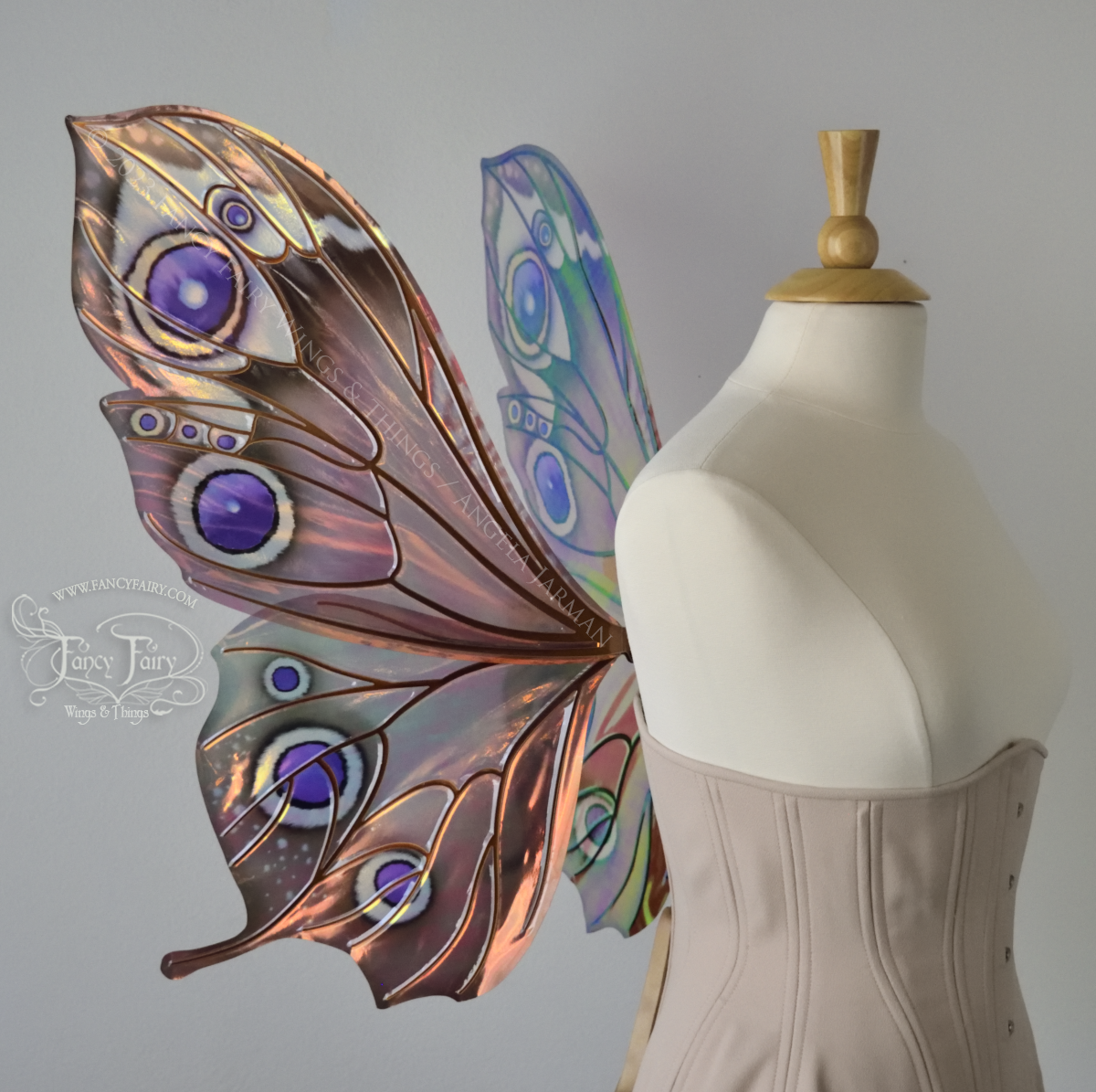 Left side view of iridescent butterfly-shaped fairy wings painted with warm autumn colors & purple and black 'eye' spots, worn on a dress form