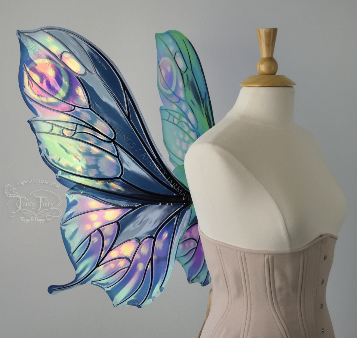 Left side view of butterfly shaped iridescent wings in shades of teal with pink and lavender accents with black veins, worn on a dressform