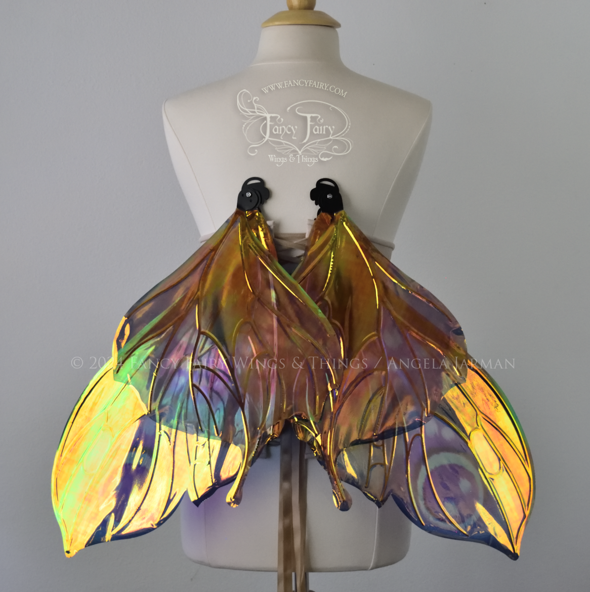 Back view of butterfly shaped iridescent wings in shades of teal with pink and lavender accents with black veins, worn on a dressform in resting position