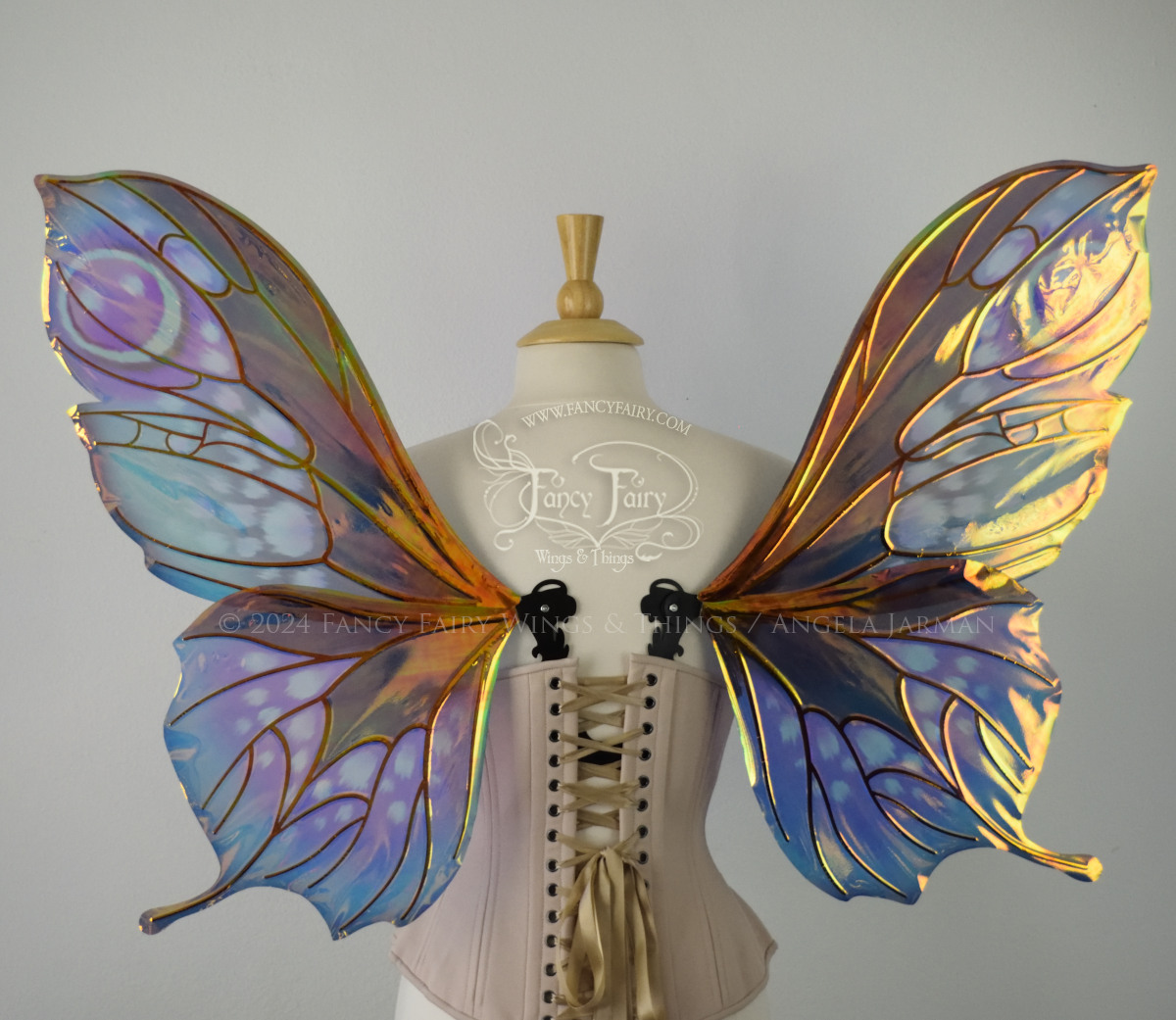 Back view of butterfly shaped iridescent wings in shades of teal with pink and lavender accents with black veins, worn on a dressform