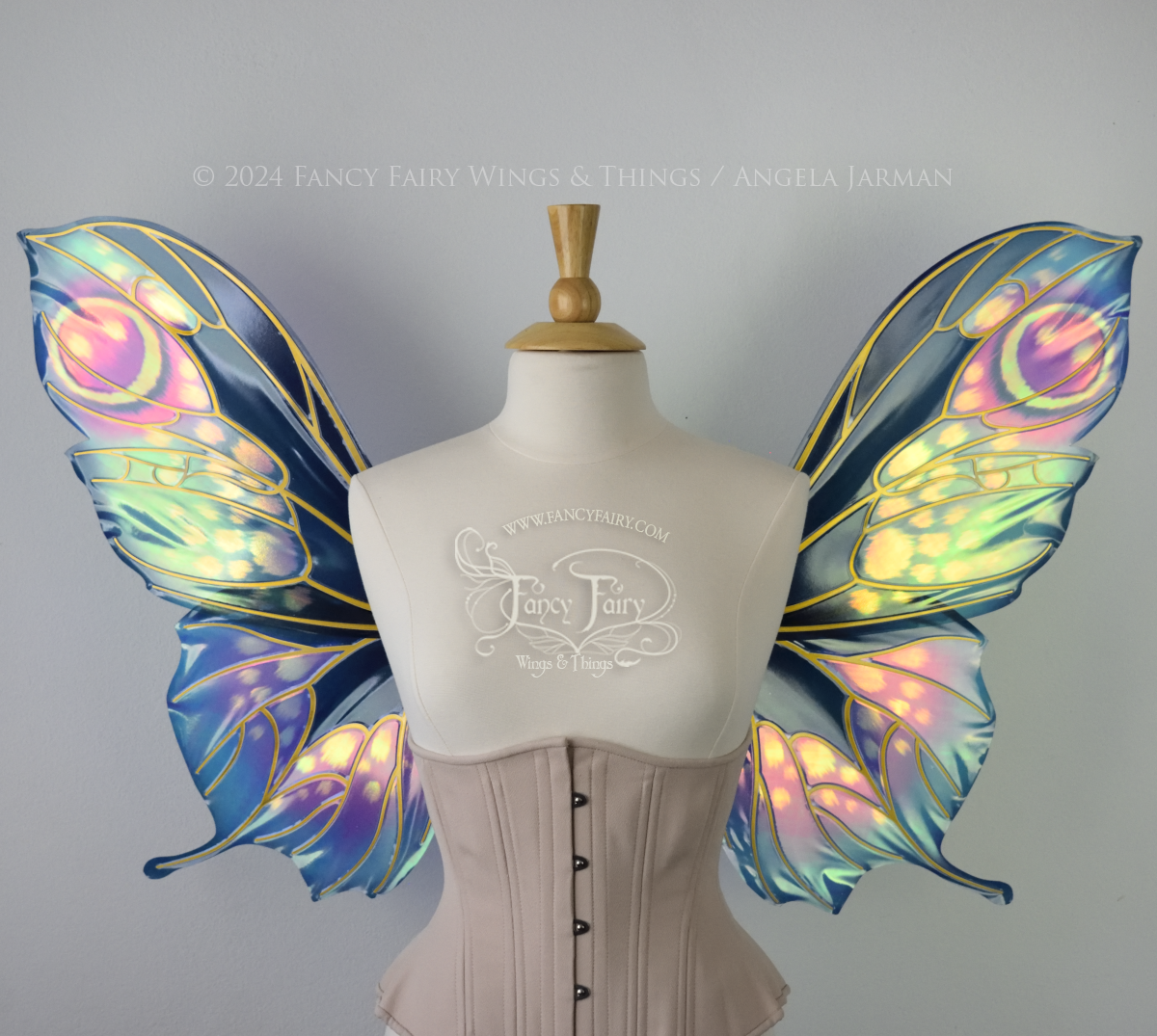 Front view of butterfly shaped iridescent wings in shades of teal with pink and lavender accents with gold veins, worn on a dressform