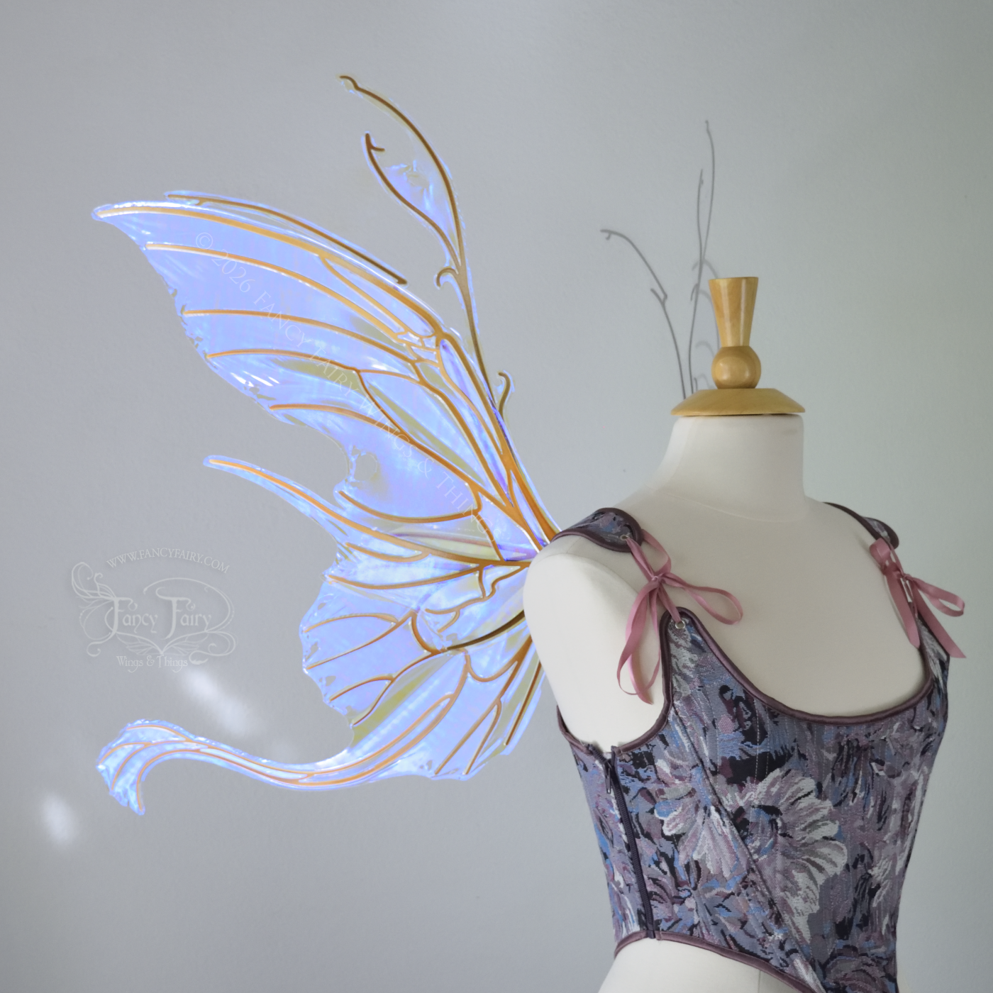 Large violet transparent iridescent fairy wings with a spikey profile and curvy tails on bottom, worn on a dress form, left side view.