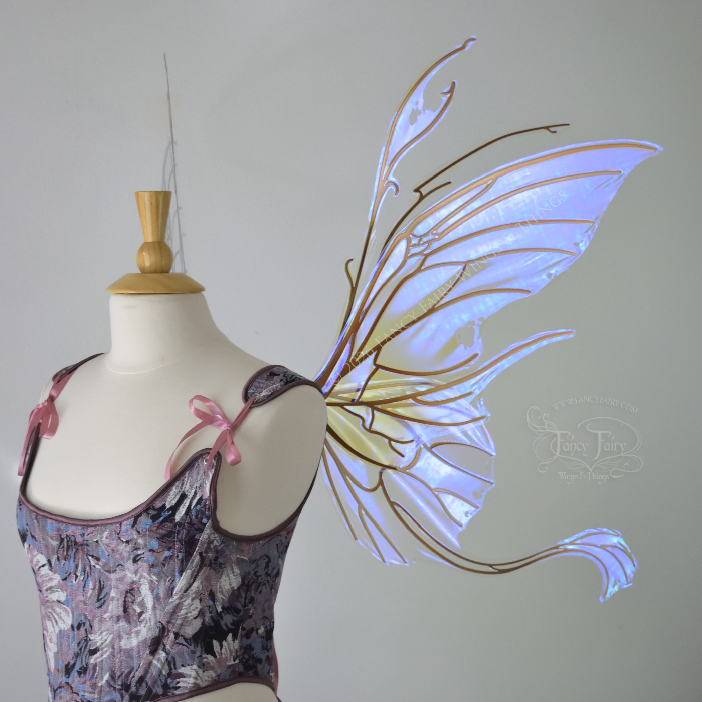 Large violet transparent iridescent fairy wings with a spikey profile and curvy tails on bottom, worn on a dress form, right side view.