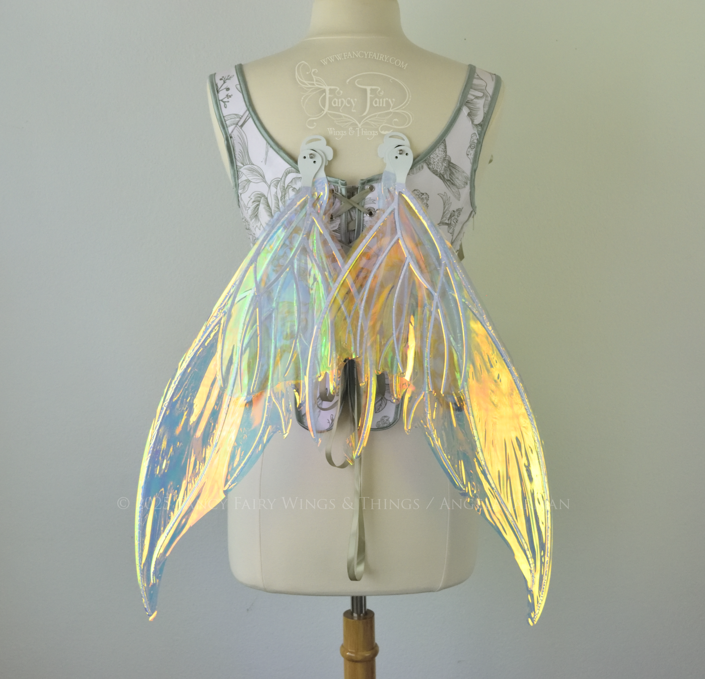 Iridescent transparent gold / orange / green fairy wings with small tails & white veins worn on a dress form, back view, in resting position