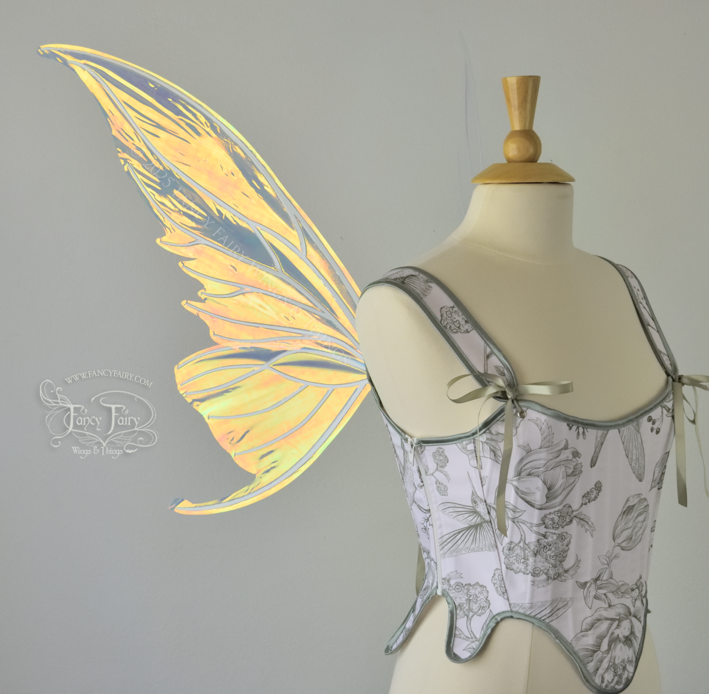 Iridescent transparent gold / orange / green fairy wings with small tails & white veins worn on a dress form, left side view