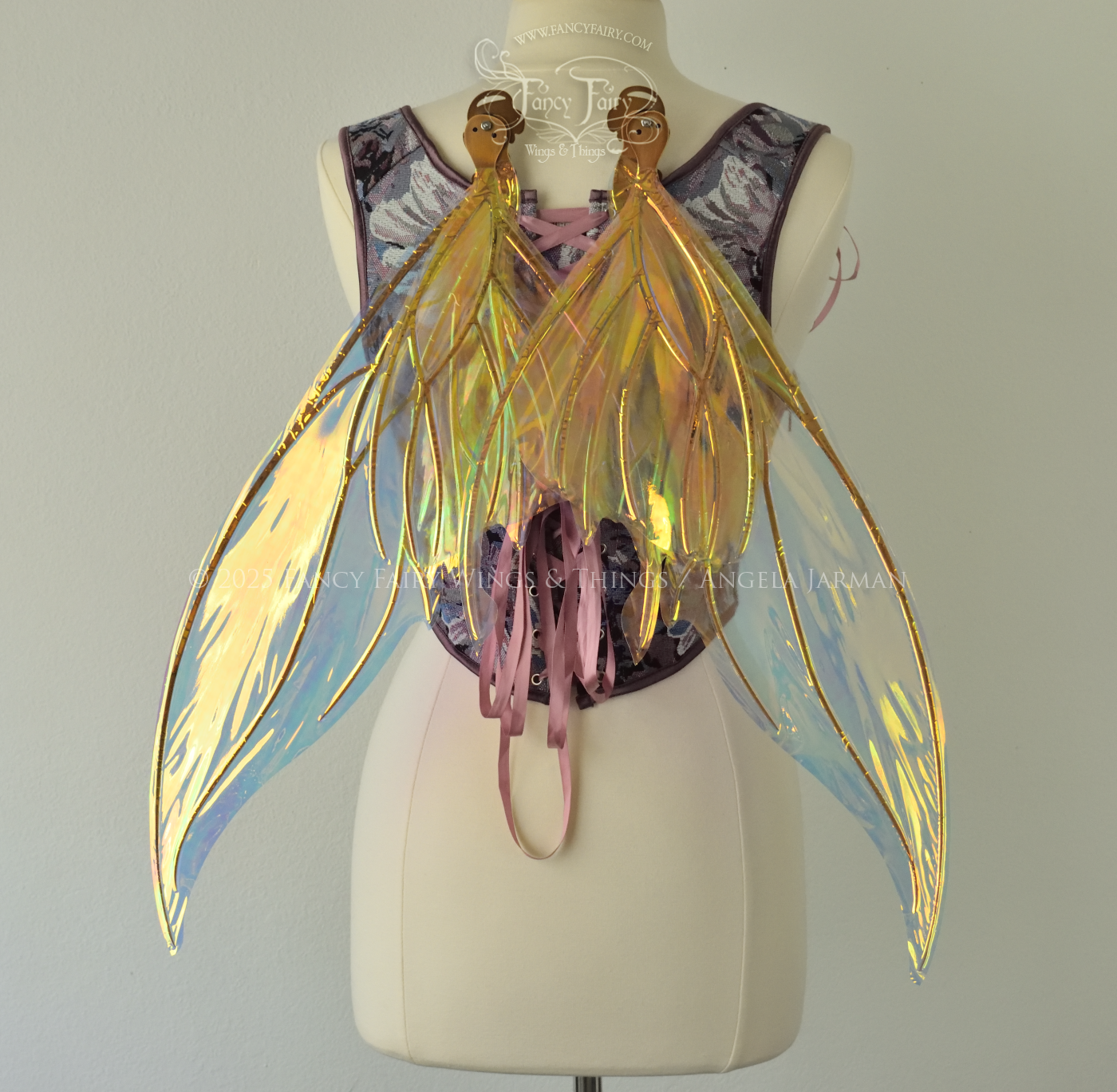 Iridescent transparent gold / orange / green fairy wings with small tails & black veins worn on a dress form, back view, in resting position