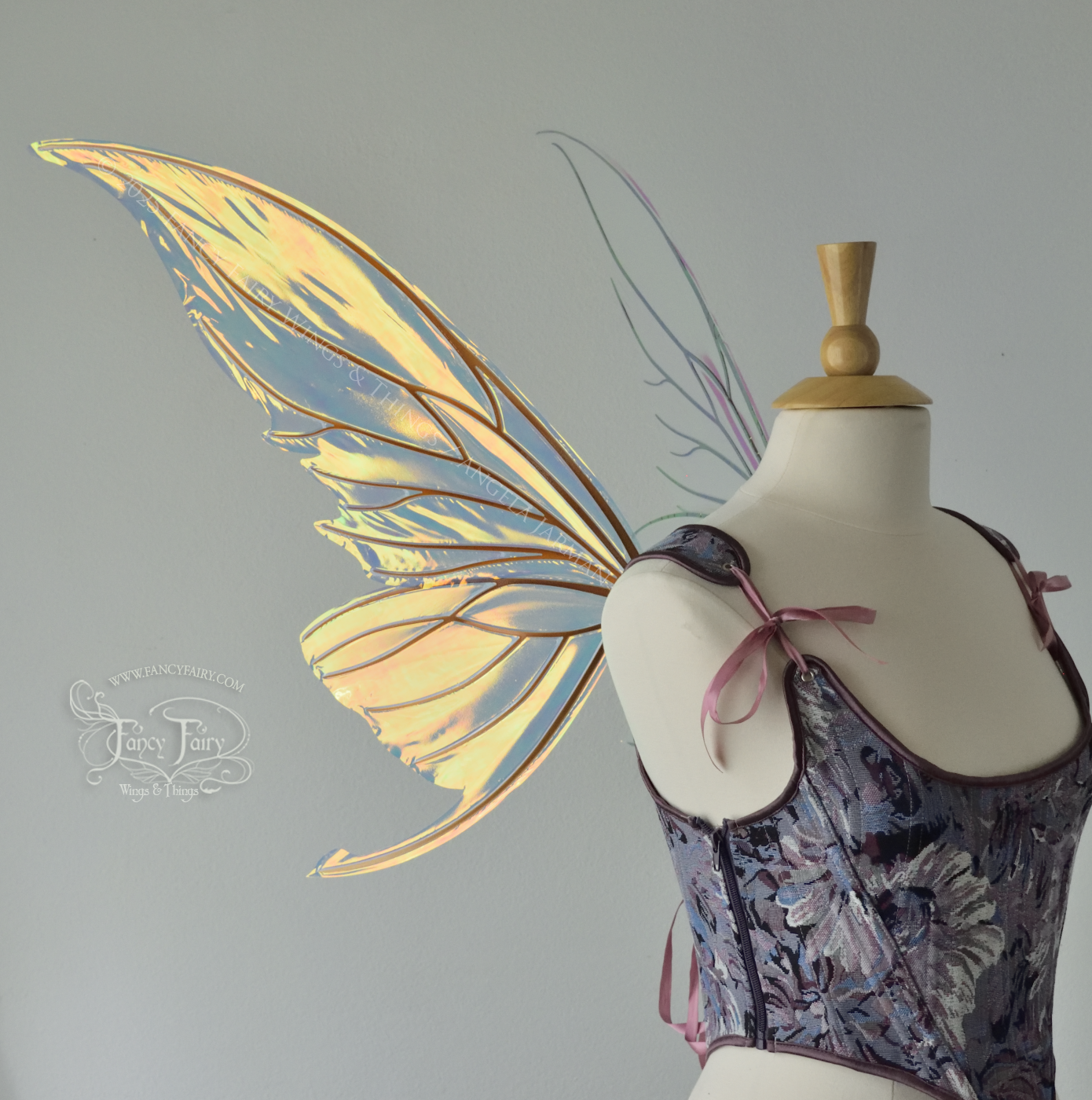 Iridescent transparent gold / orange / green fairy wings with small tails & black veins worn on a dress form, left side view