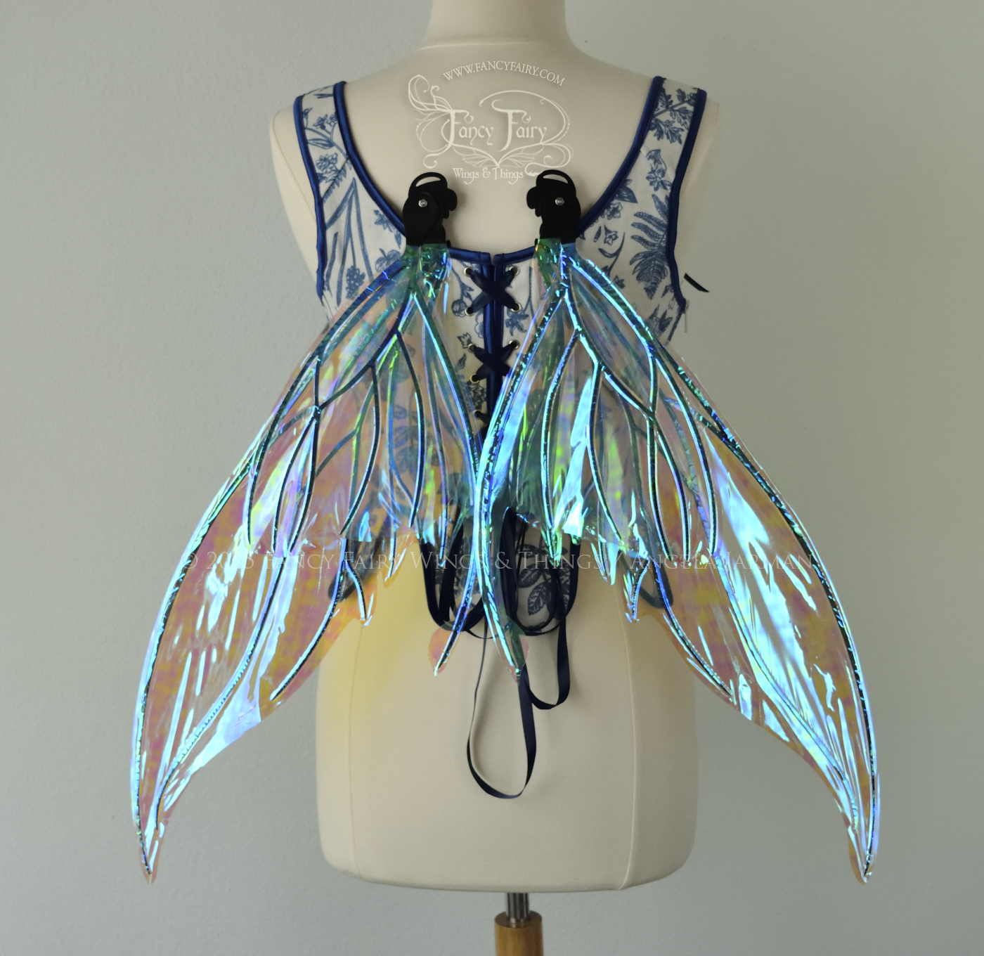 Iridescent transparent blue fairy wings with small tails & black veins worn on a dress form, back view, in resting position