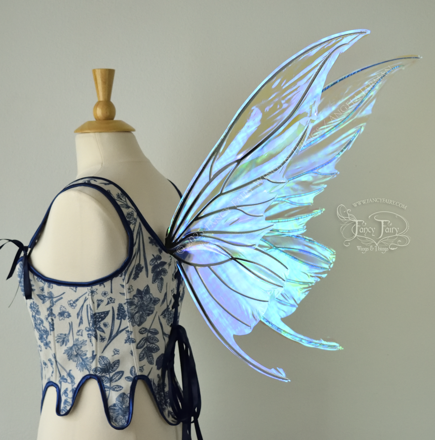 Iridescent transparent blue fairy wings with small tails & black veins worn on a dress form, back 3/4 view