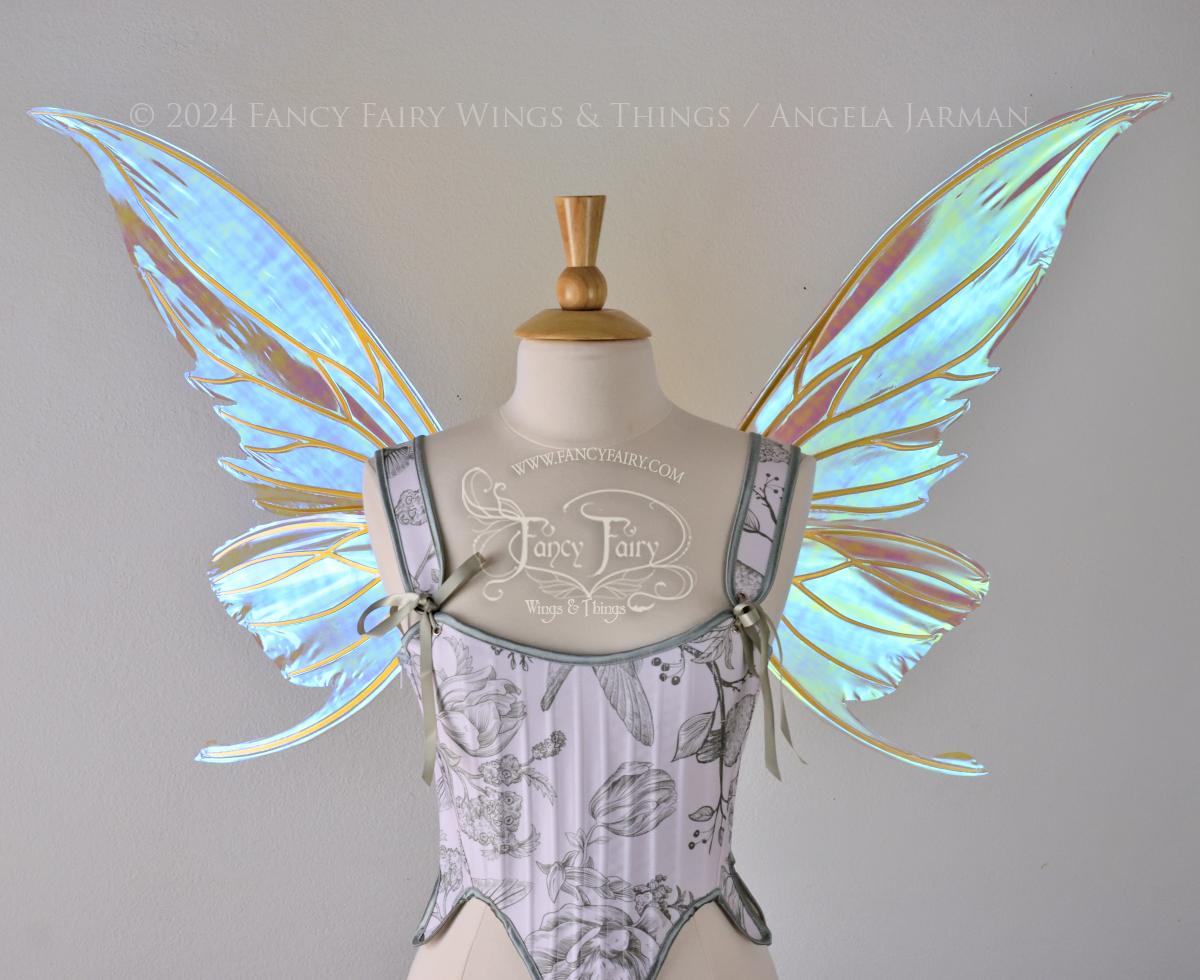 Large blue green iridescent fairy wings with gold veins worn with a white & sage green bodice on a dress form