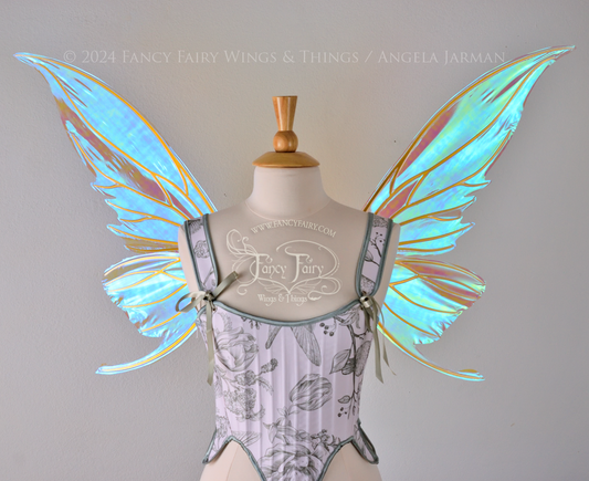 Large blue green iridescent fairy wings with gold veins worn with a white & sage green bodice on a dress form