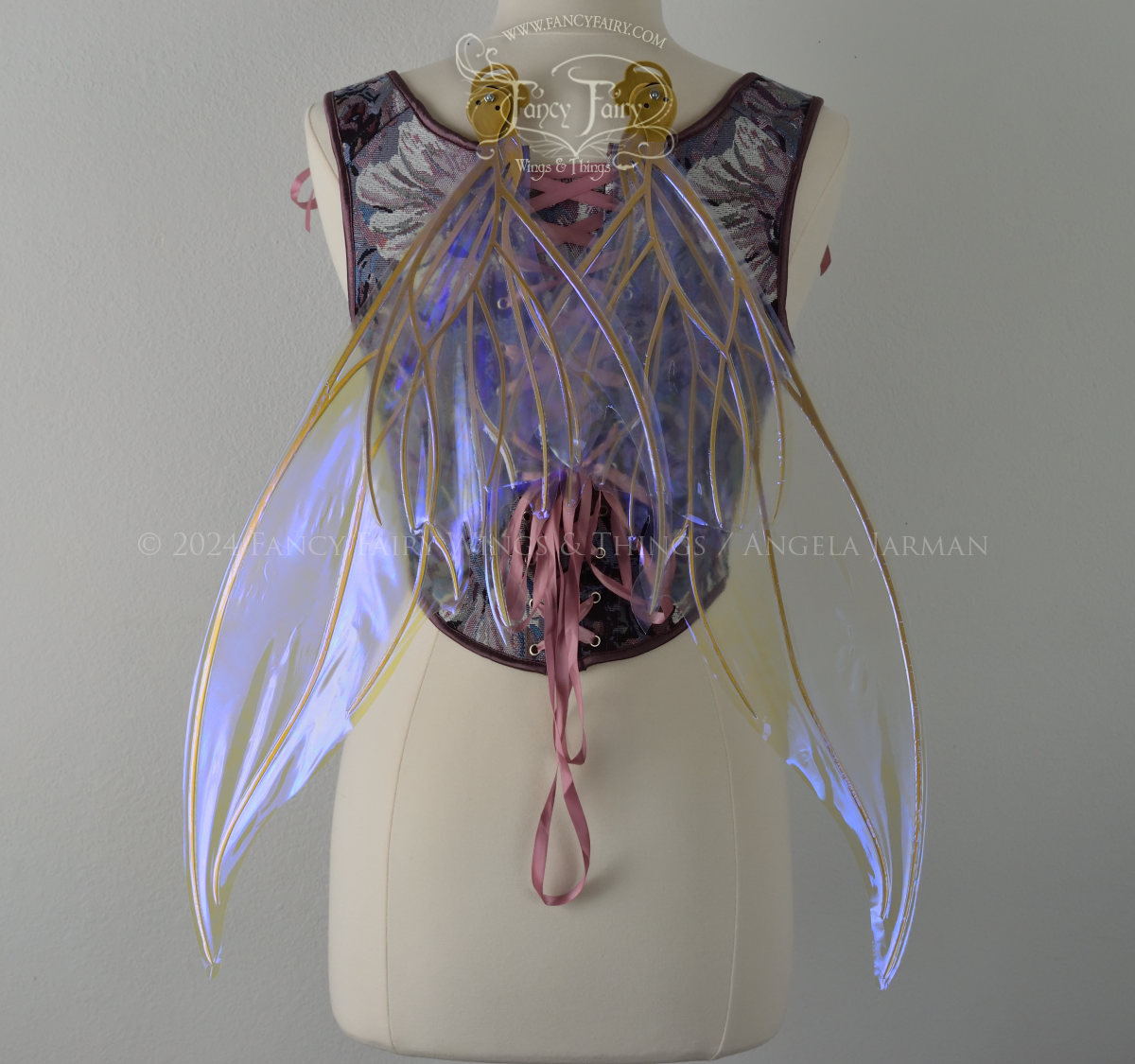 Large violet iridescent fairy wings with gold veins worn with a purple bodice on a dress form, back view, in resting position