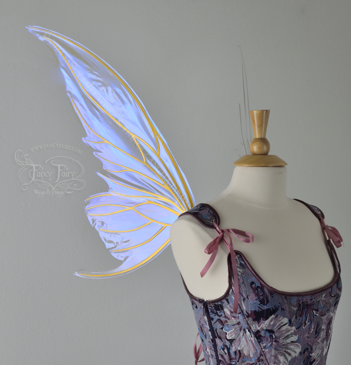 Large violet iridescent fairy wings with gold veins worn with a purple bodice on a dress form, left side view