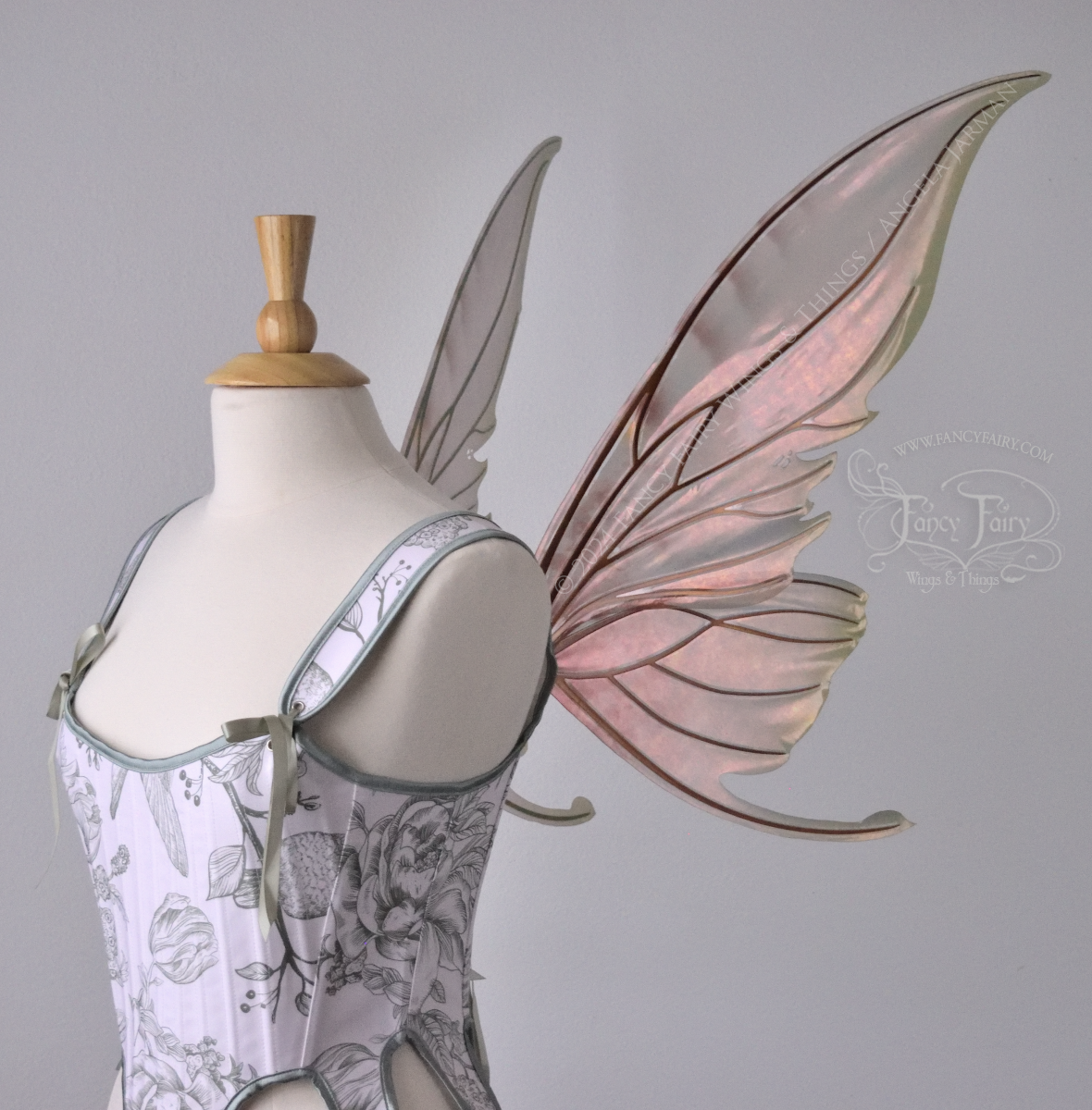 Large coppery iridescent fairy wings with brown and green accents, copper veins, worn with a white & sage green bodice on a dress form, right side view