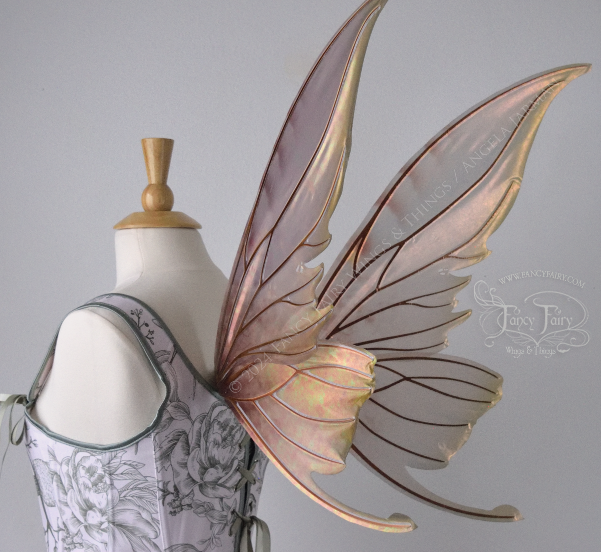 Large coppery iridescent fairy wings with brown and green accents, copper veins, worn with a white & sage green bodice on a dress form, back 3/4 view