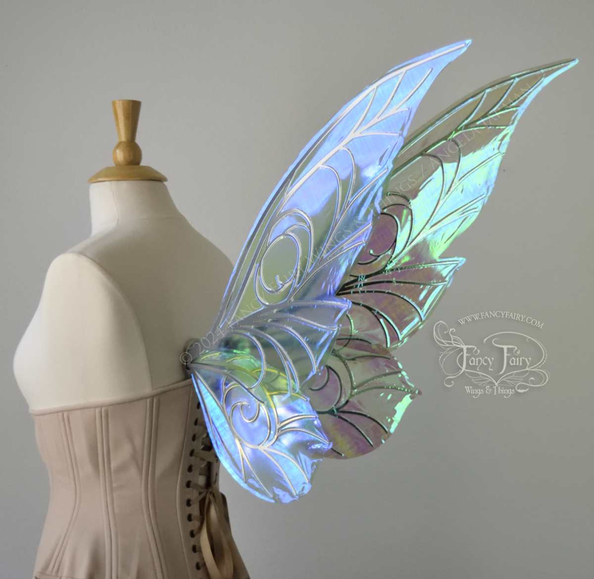 Back 3/4 view of green iridescent Tinker Bell inspired fairy wings with swirly silver veins, displayed on a dress form