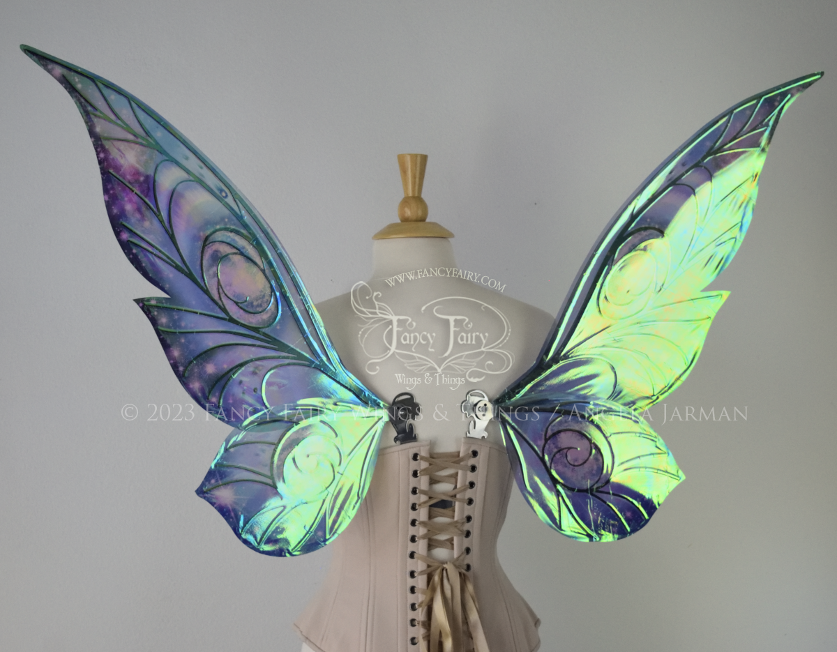 Back view of celestial iridescent fairy wings with blue skies, fuchsia nebulas, auroras and stars, with silver veins, worn on a dress form 
