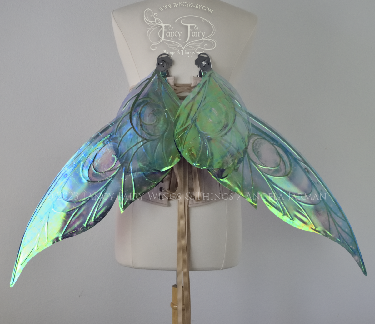 Back view of celestial iridescent fairy wings with blue skies, fuchsia nebulas, auroras and stars, with silver veins, worn on a dress form, in resting position