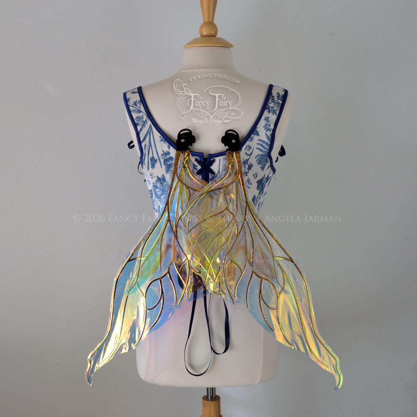 Transparent iridescent fairy wings with wavy tips and black veins, worn on a dress form, back view, in resting position