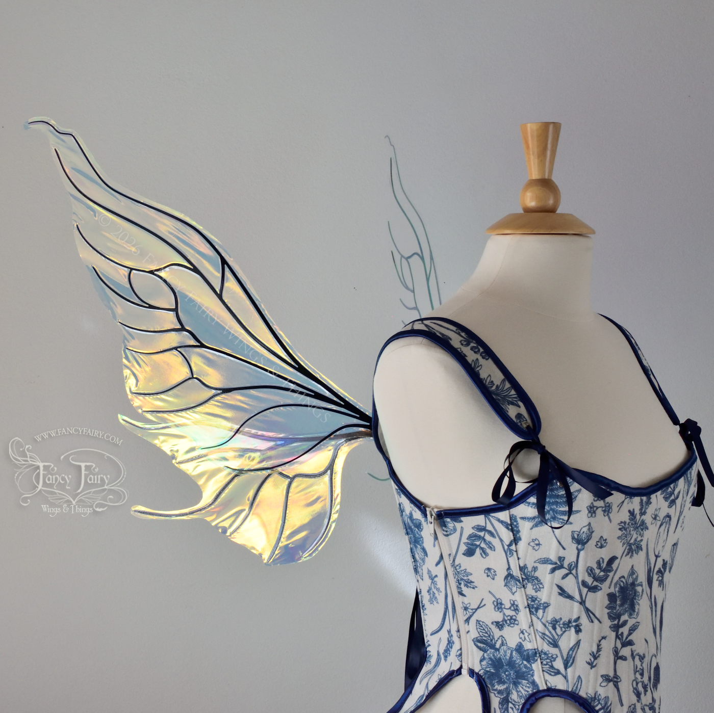 Transparent iridescent fairy wings with wavy tips and black veins, worn on a dress form, left side view
