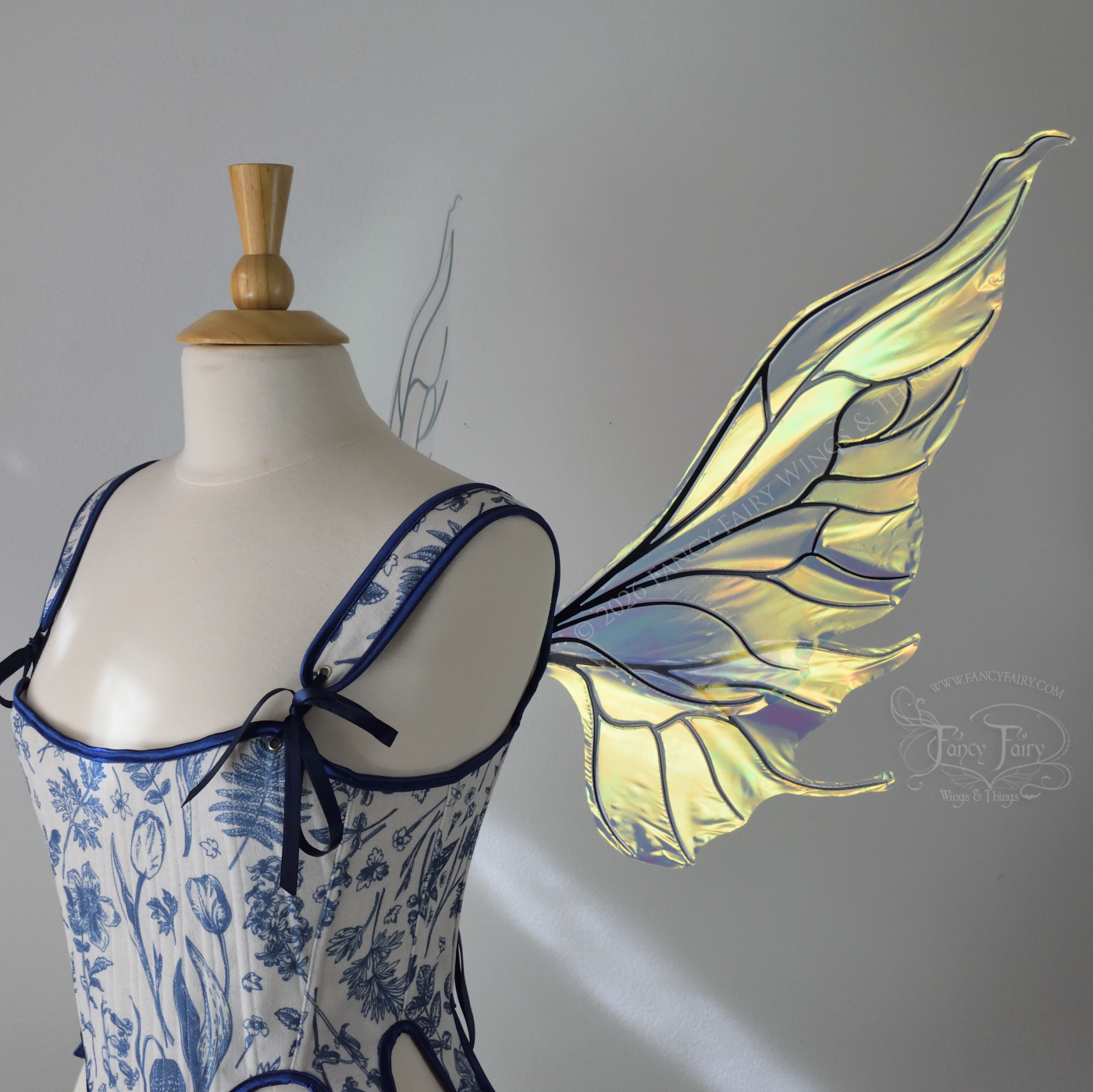 Transparent iridescent fairy wings with wavy tips and black veins, worn on a dress form, right side view