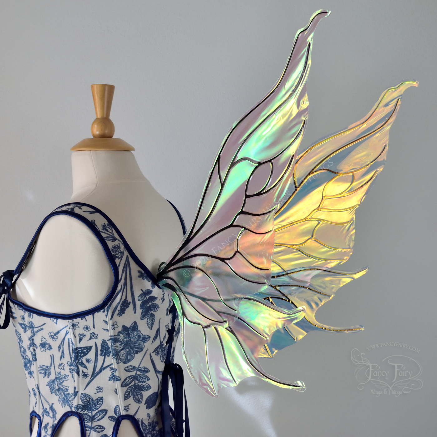 Transparent iridescent fairy wings with wavy tips and black veins, worn on a dress form, back 3/4 view