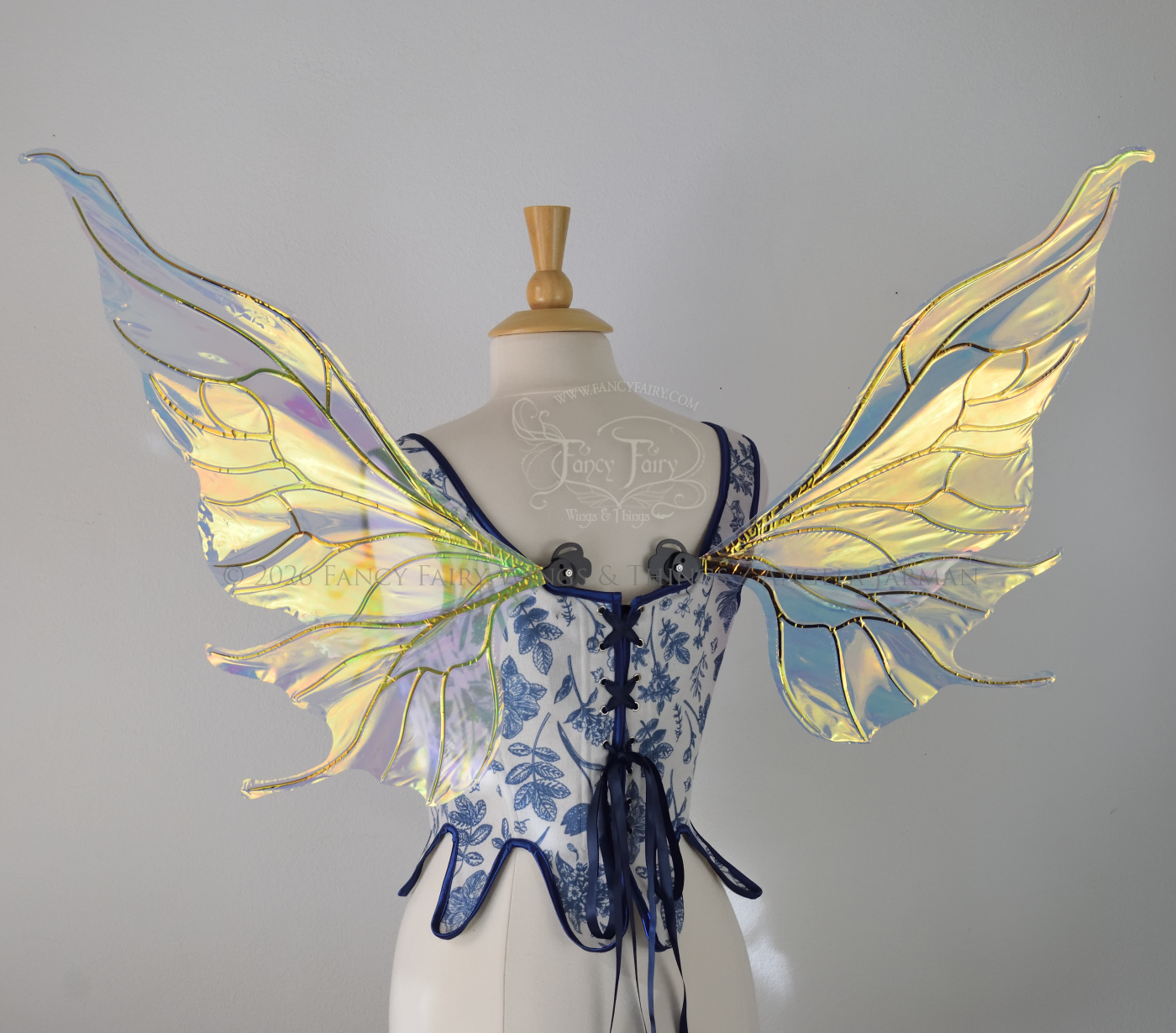 Transparent iridescent fairy wings with wavy tips and black veins, worn on a dress form, back view