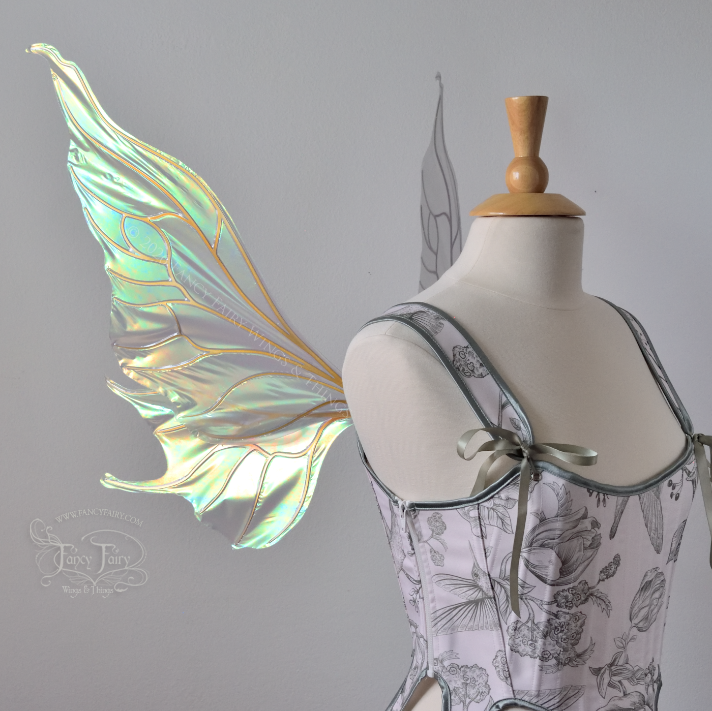Sheer green iridescent fairy wings with wavy tips and gold veins, worn on a dress form, left side view