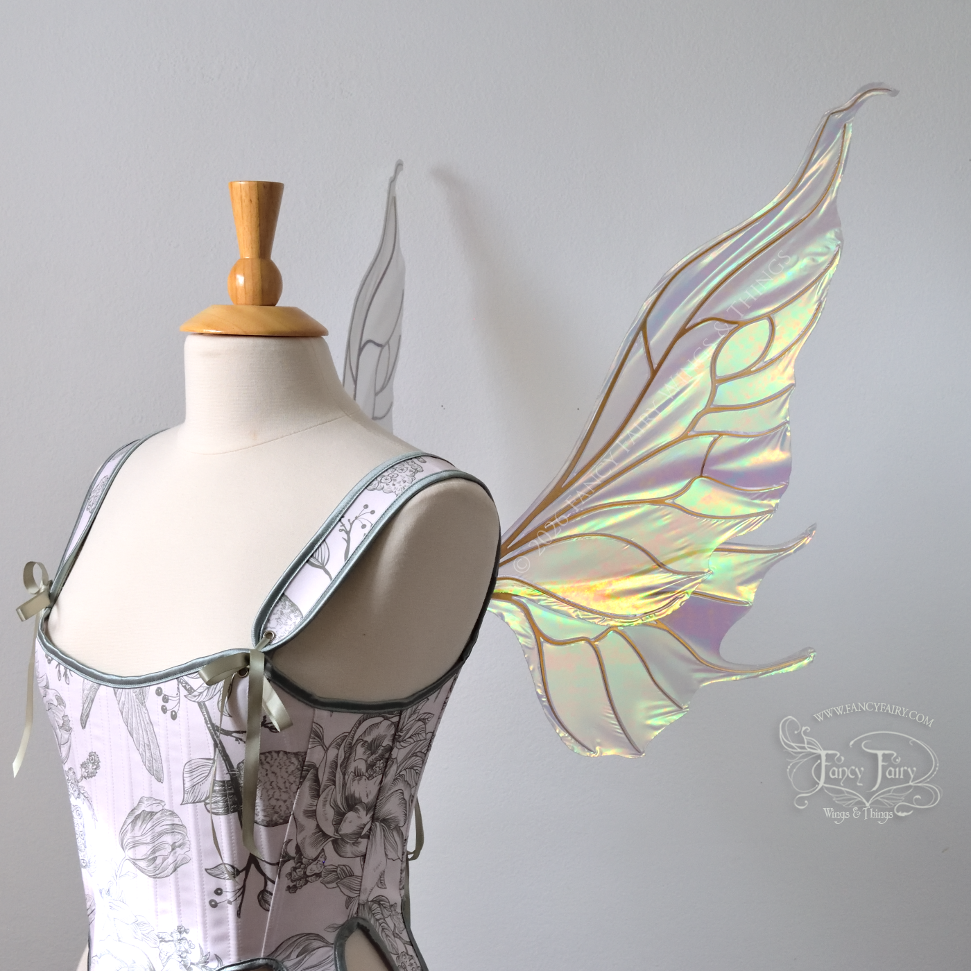 Sheer green iridescent fairy wings with wavy tips and gold veins, worn on a dress form, left side view