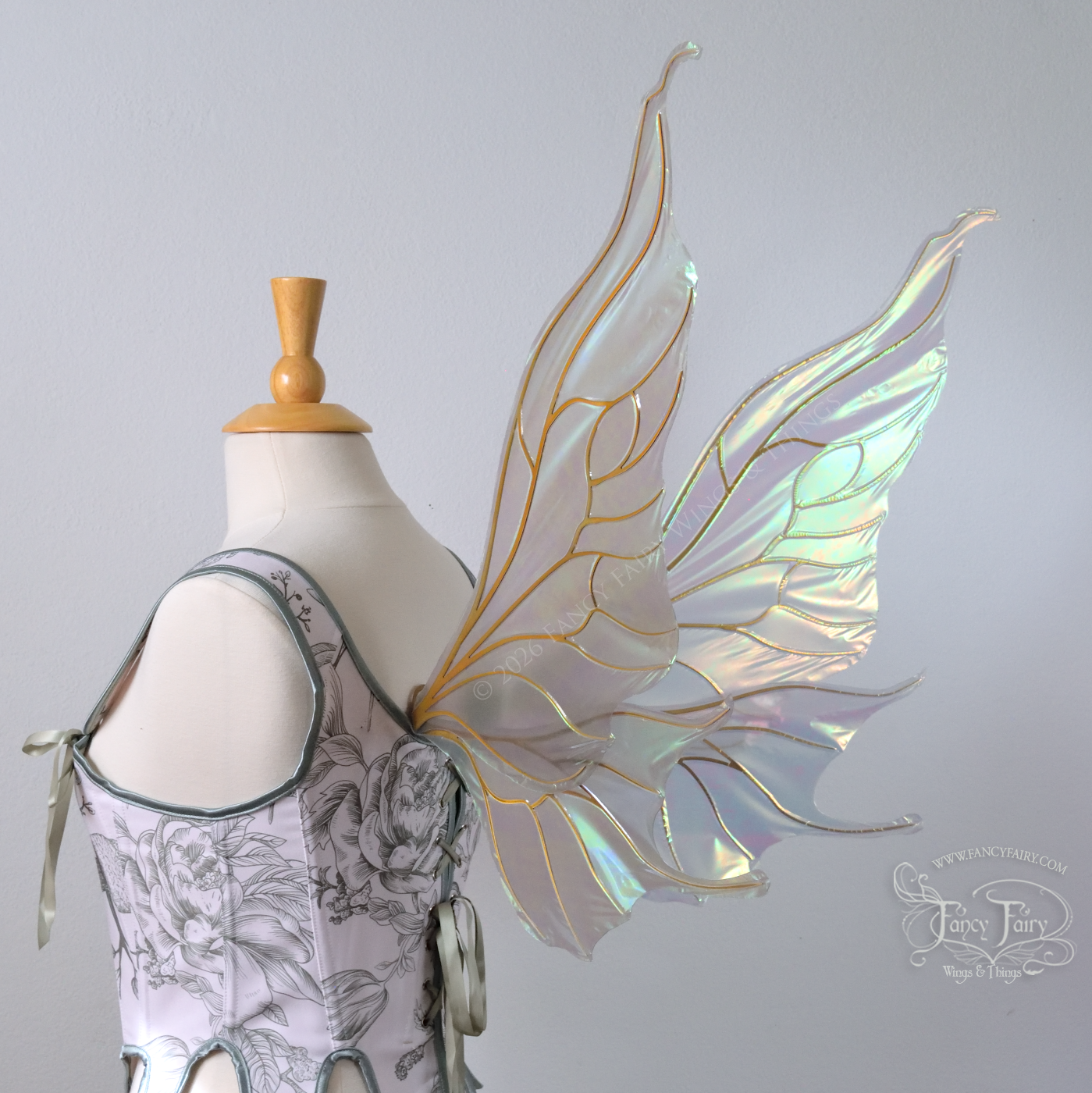 Sheer green iridescent fairy wings with wavy tips and gold veins, worn on a dress form, back 3/4 view